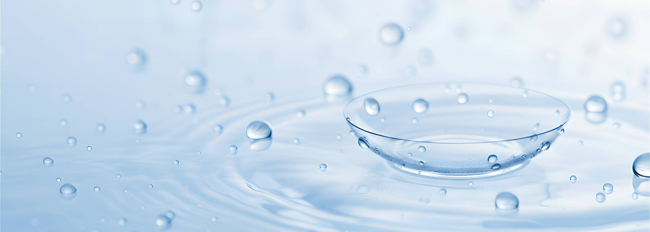 Kontaktlinse und Wassertropfen auf Oberfläche