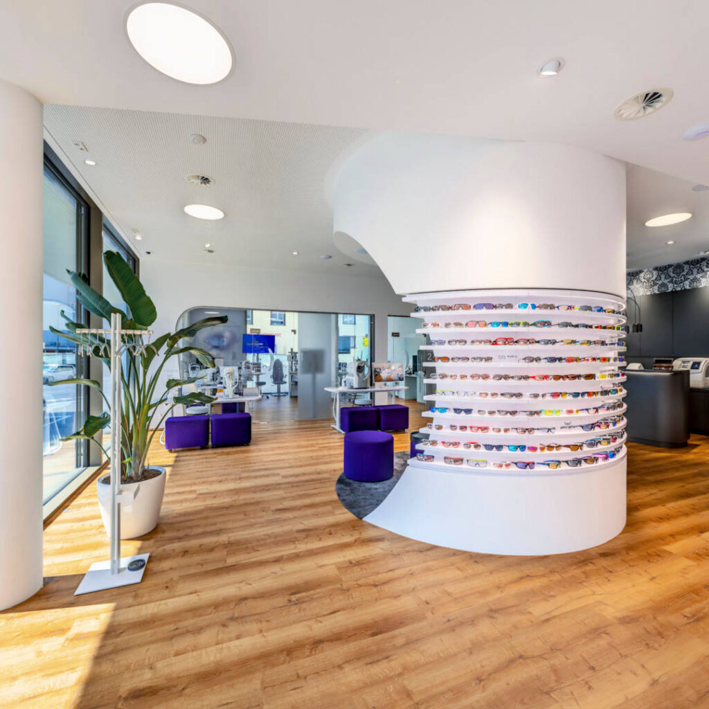 Raumtrenner Insel mit Brillenregal und Betreuungsraum im Hintergrund